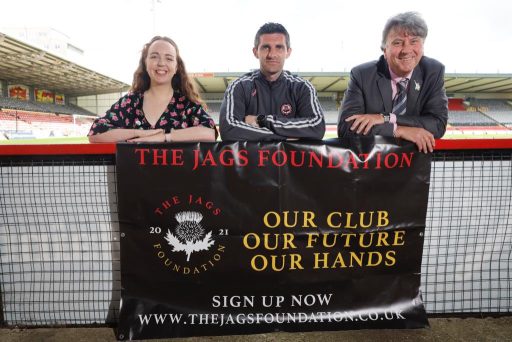 Kris Doolan with TJF directors Heather Holloway and Stuart Callison, standing with a Jags Foundation banner